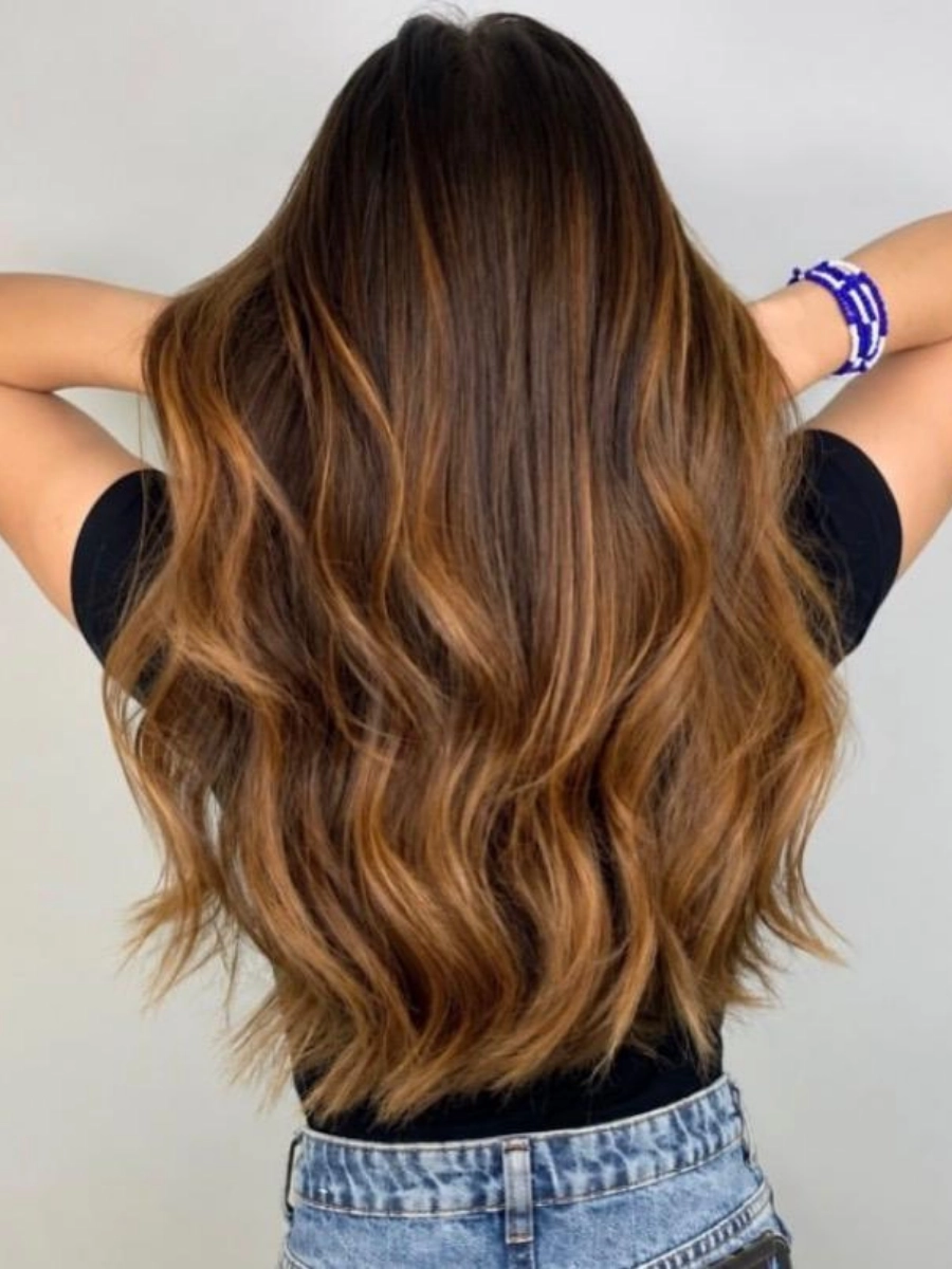Cabelo castanho longo com mechas iluminadas e ondas